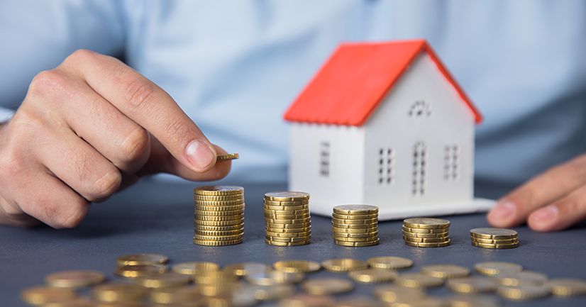 man hand coins with house model on desk; Immobilienkauf