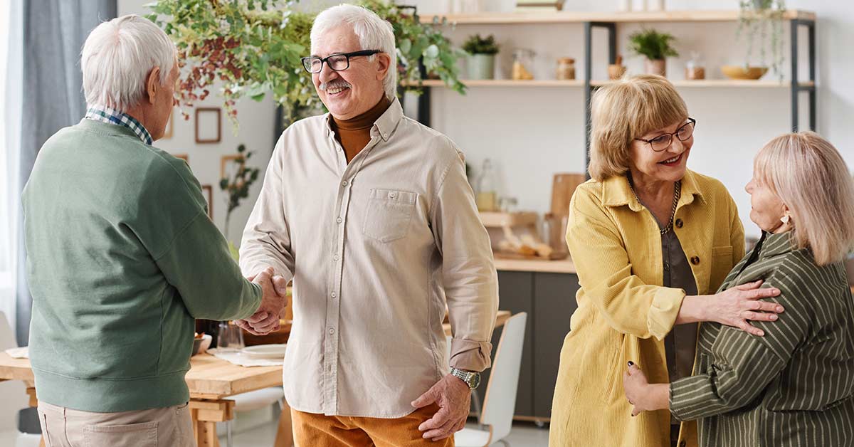 Vier Senioren begrüßen sich in ihrer gemeinsamen WG | Senioren Wohngemeinschaft