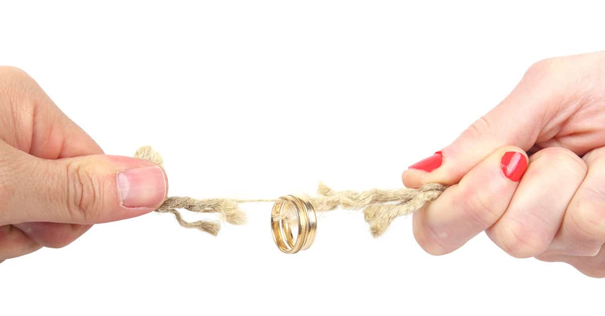 Zwei Hände ziehen an einem Strick, der reißt und an dem ein Ehering hängt | Wohnrecht Scheidung