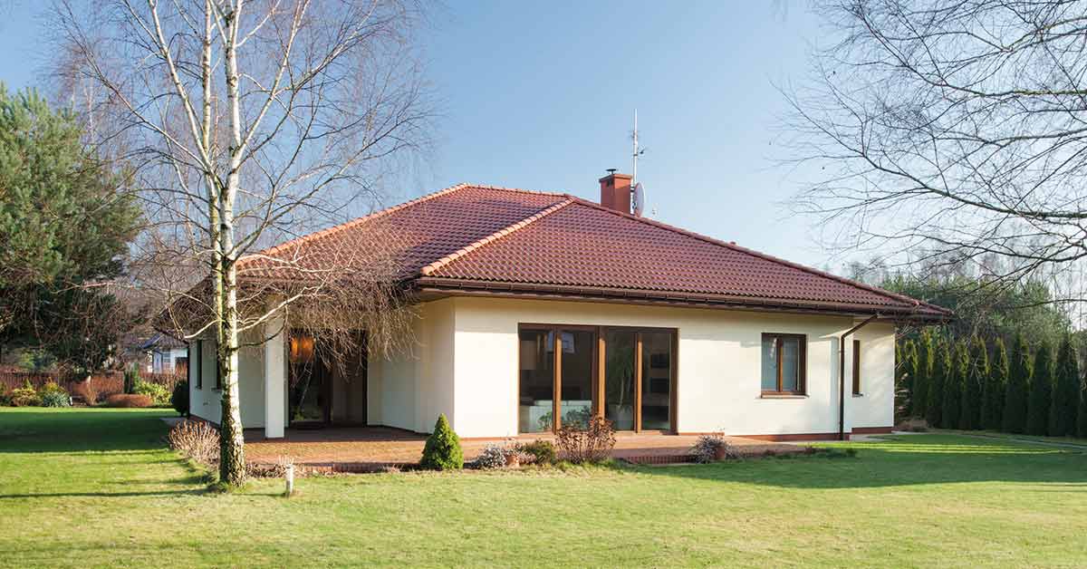 Ein Haus mit Garten unter blauem Himmel mit Bäumen | Altervorsorge Immobilie