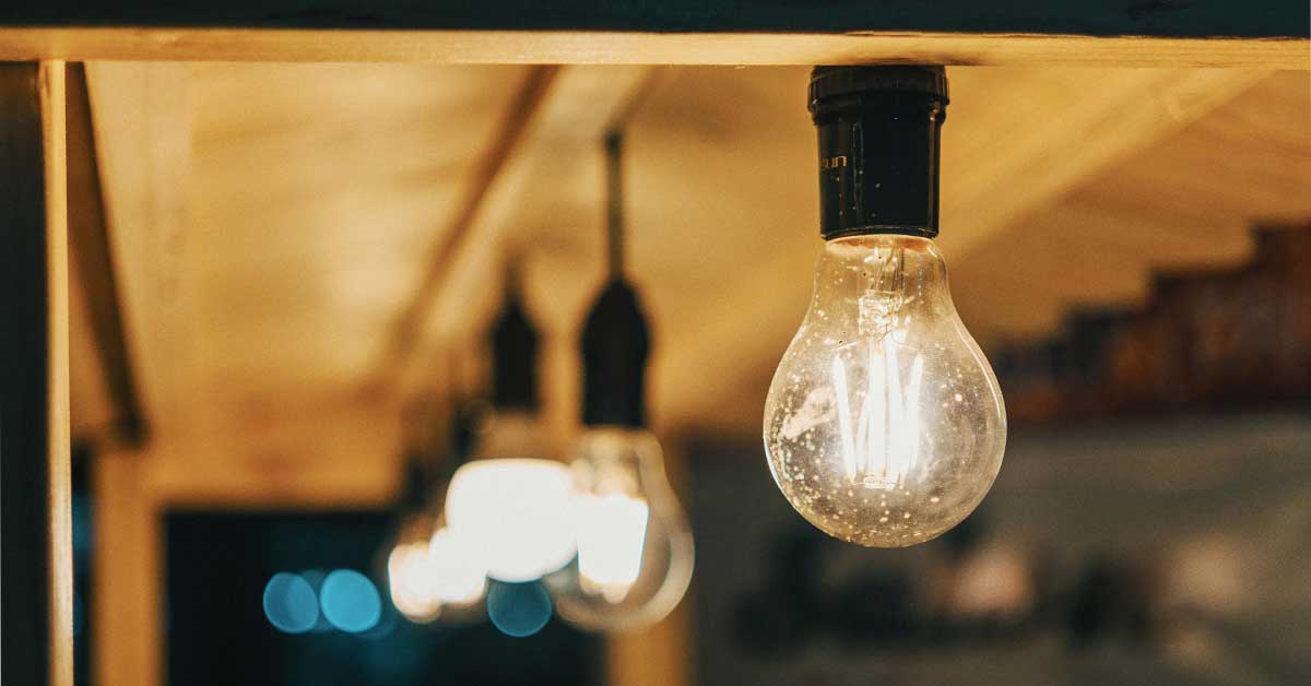 Leuchtende Glühbirnen, die an einer Decke hängen und den Strompreis symbolisieren